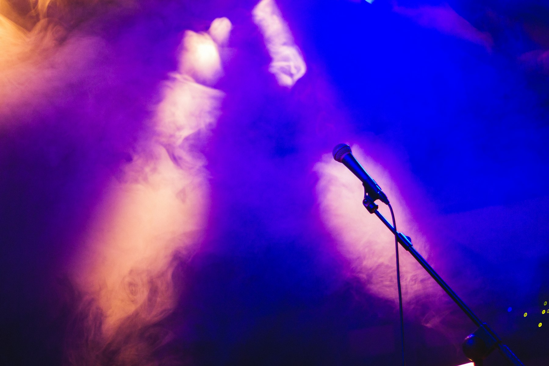 A real stage microphone under vivid blue and purple lights
